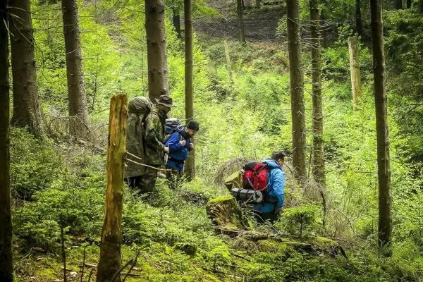 Gruppe untersucht den Boden im Wald, umgeben von Bäumen und Sträuchern