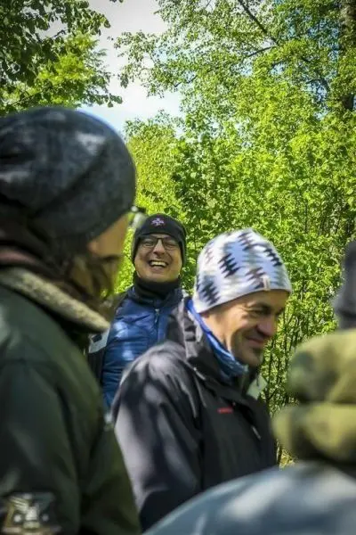 Gruppe von Personen in Outdoor-Bekleidung steht im Grünen und lacht