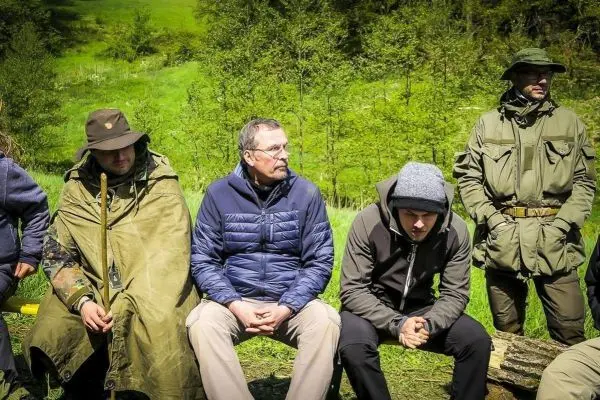 Gruppe von Personen sitzt auf einem Baumstamm im Freien