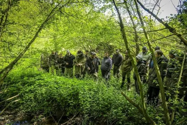 Gruppe von Personen steht im dichten Grün eines Waldes