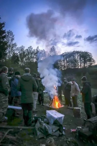 Gruppe von Personen versammelt sich um ein Feuer im Freien