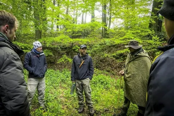 Gruppendiskussion im Wald über Überlebenstechniken und Naturkunde