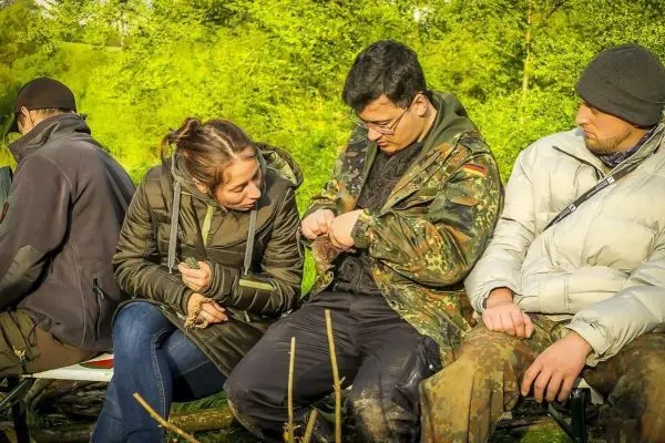 Gruppensitzung im Freien, Teilnehmer diskutieren und zeigen Ausrüstung