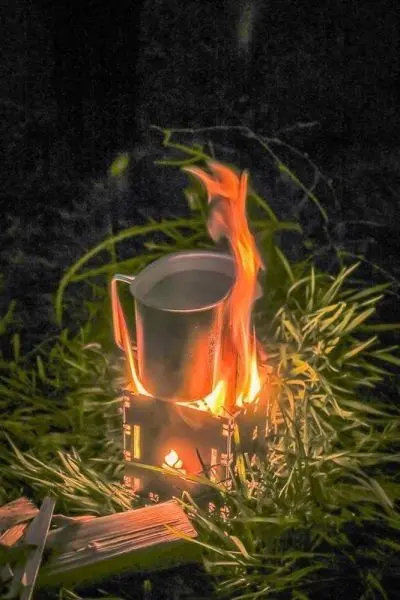 Kessel auf Hobo-Kocher mit Flamme und glühendem Zunder