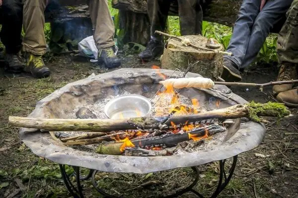 Kleine Flamme brennt in einer Feuerstelle mit Holz und einem Topf
