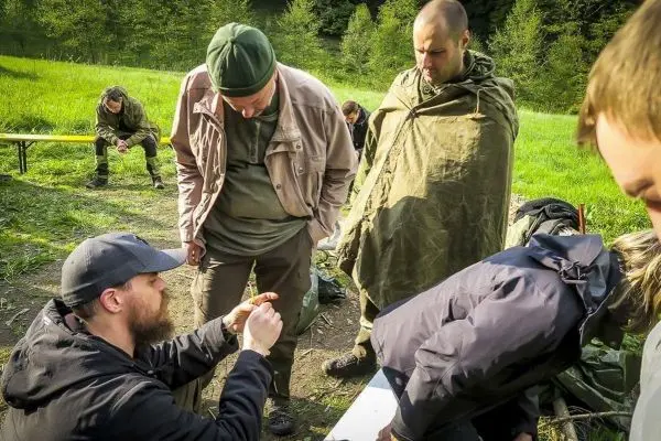 Mann demonstriert Technik mit einem kleinen Gegenstand, umringt von mehreren Personen
