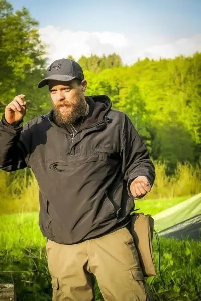 Mann gestikuliert im Freien vor einer Tarp-Notunterkunft