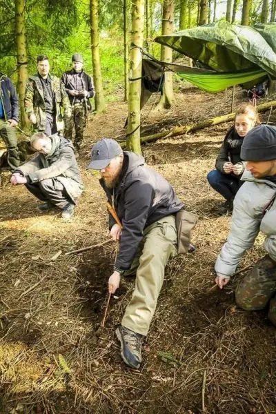 Mann gräbt mit einem Stock in der Erde, während andere zuschauen