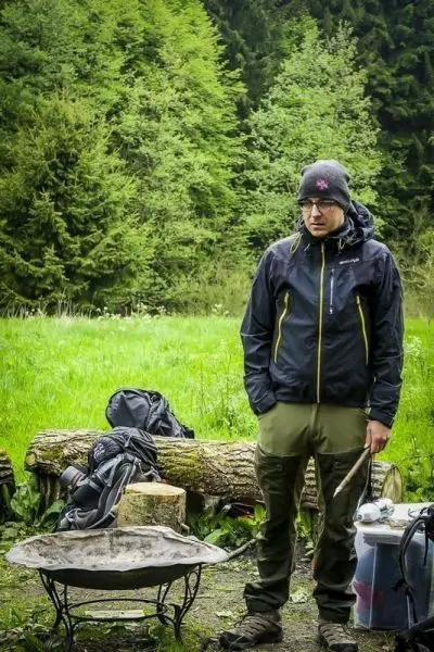 Mann steht neben einem Feuerstelle aus Metall im Wald