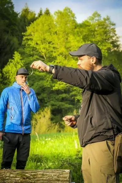 Mann zeigt ein kleines Objekt in der Hand, während ein anderer Mann im Hintergrund zuschaut