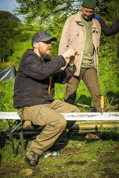 Messer bearbeitet Holzstück auf einer Klappbank im Freien