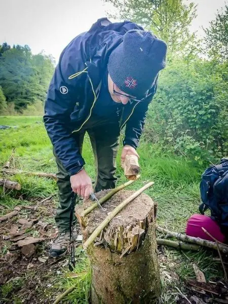 Messer schneidet Holzstück auf einem Baumstumpf in der Natur