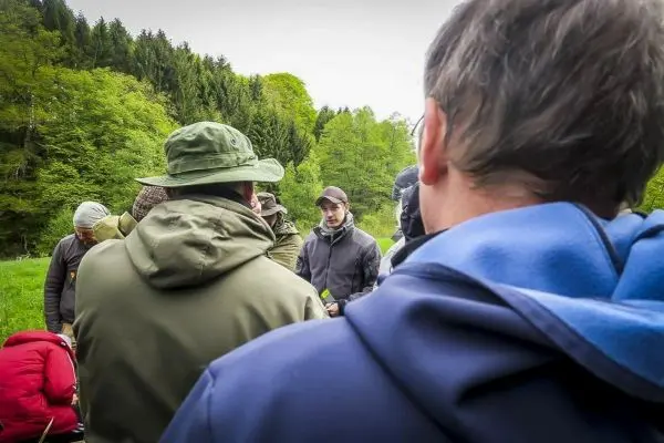 Person erklärt etwas einer Gruppe im Freien beim Überlebenstraining