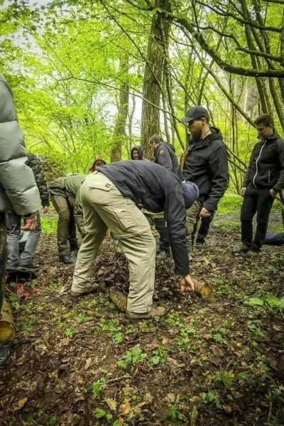 Teilnehmer arbeiten am Boden mit Holzstücken im Wald