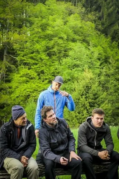 Vier Personen sitzen auf einer Bank vor einer grünen Waldlandschaft