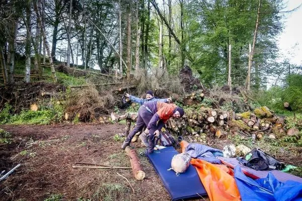 Zwei Personen packen Ausrüstung auf einer Matte im Wald