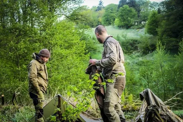 Zwei Personen richten eine Tarp-Notunterkunft im Wald ein