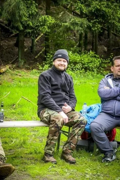 Zwei Personen sitzen auf einer Bank in der Natur, umgeben von Bäumen