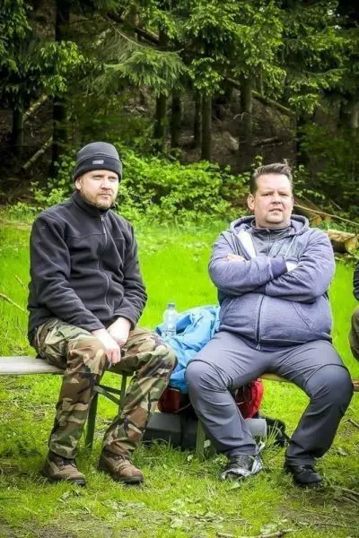 Zwei Personen sitzen auf einer Bank in einer grünen Umgebung