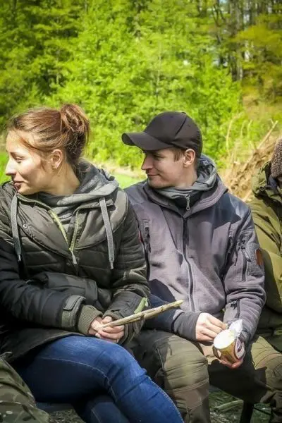Zwei Personen sitzen nebeneinander, eine hält einen Stock und eine Tasse