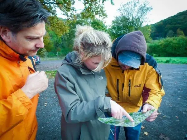 Drei Personen betrachten gemeinsam eine Karte im Freien