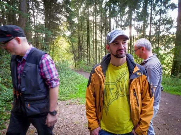 Drei Personen stehen auf einem Waldweg und unterhalten sich