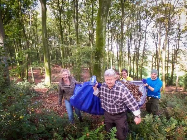 Gruppe trägt große Säcke mit Laub durch den Wald