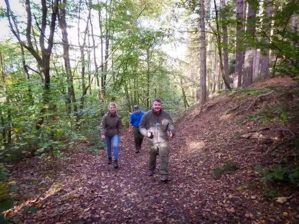 Gruppe wandert auf einem Waldweg zwischen Bäumen und Laub