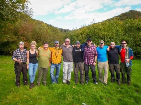 Gruppierung von zehn Personen in einem grünen Feld mit Bäumen im Hintergrund