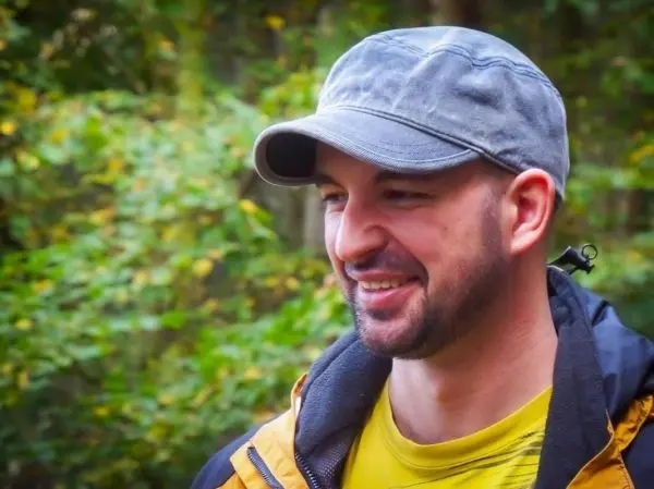Lächelnder Mann mit grauem Hut und gelbem Shirt in der Natur