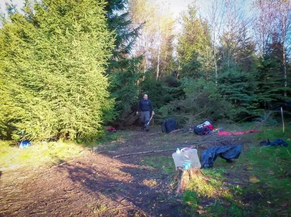 Lagerplatz mit Ausrüstung, Holzstück und Person im Wald