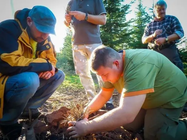 Mann bereitet Zunder auf dem Boden vor, während andere beobachten