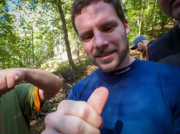 Mann betrachtet seinen Daumen im Wald, Hände von anderen Personen im Hintergrund