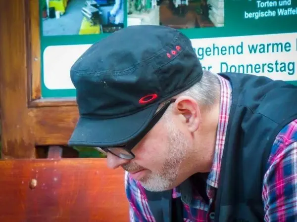 Mann mit schwarzer Mütze und kariertem Hemd sitzt auf einer Bank