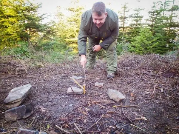 Mann positioniert einen Stock auf einer improvisierten Schlagfalle aus Steinen