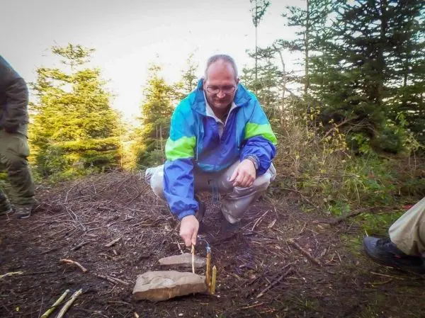 Mann zündet Zunder mit einem Feuerstahl auf einem Stein