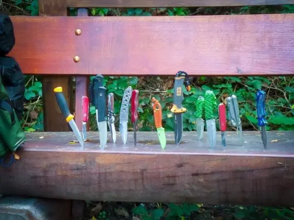 Mehrere Messer in unterschiedlichen Größen und Designs auf einer Holzbank angeordnet