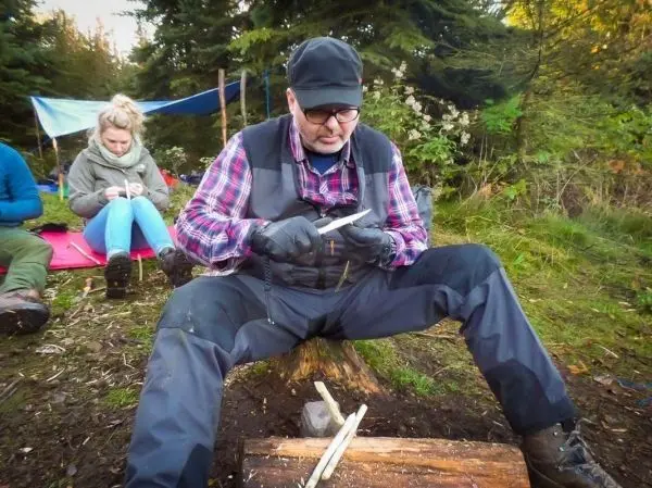 Messer bearbeitet Holzstück auf einem Baumstumpf im Wald