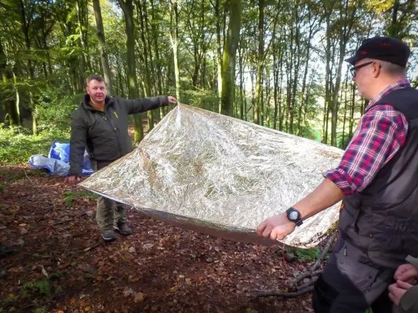 Person hält eine reflektierende Decke in einem Wald