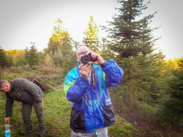 Person hält Kamera und fotografiert im Wald