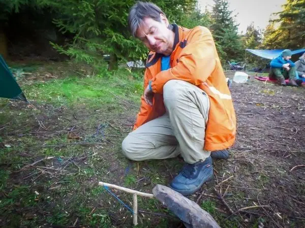 Person kniet und betrachtet eine selbstgebaute Vorrichtung aus Holz