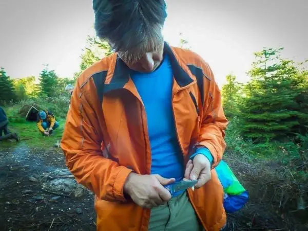 Person schneidet mit einem Messer etwas in der Natur