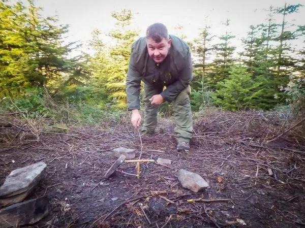 Schlagfalle (Figure-Four) mit Steinen und Holzstücken aufgebaut