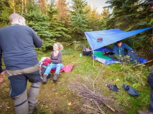 Tarp-Notunterkunft bietet Schutz, während zwei Personen im Wald entspannen
