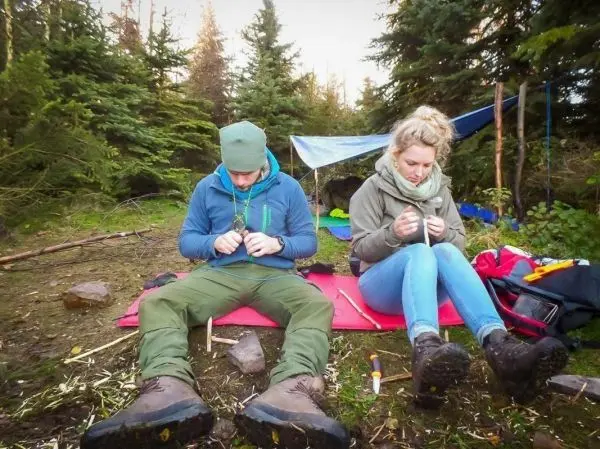 Zwei Personen bearbeiten Material auf einer roten Unterlage im Wald
