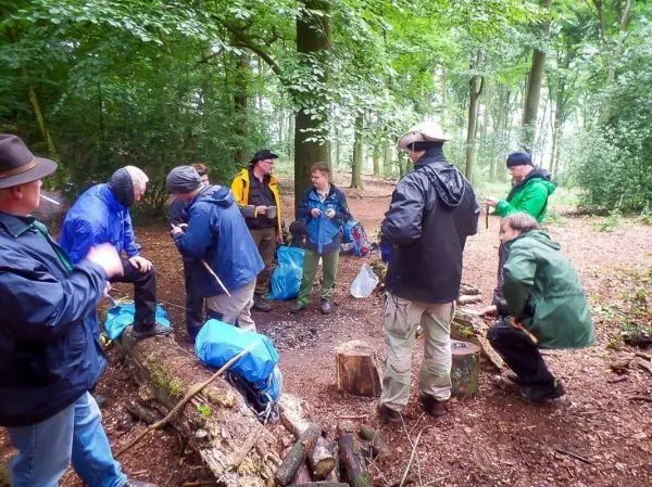 Gruppe arbeitet an einem Lagerfeuer mit Holz und Ausrüstung im Wald