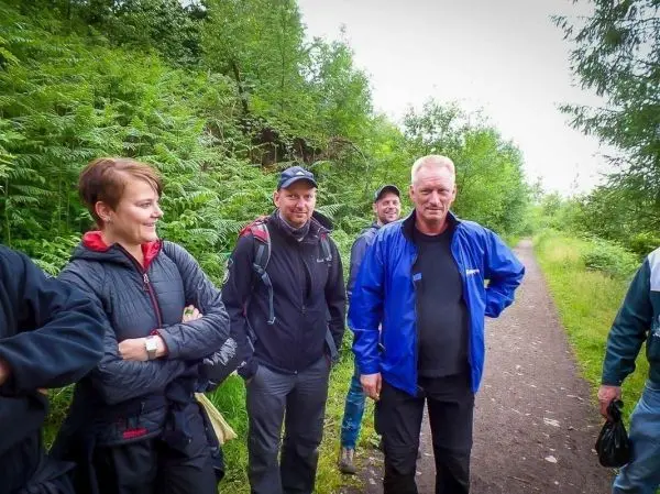 Gruppe steht auf einem Waldweg, umgeben von Bäumen und Sträuchern