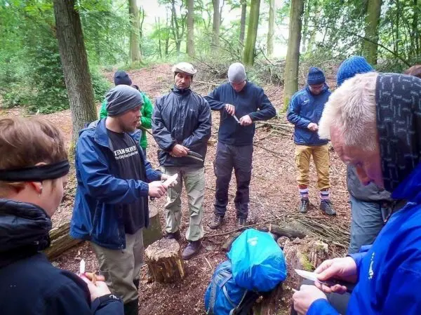 Gruppe übt Holzarbeit mit Messern in einem Waldgebiet