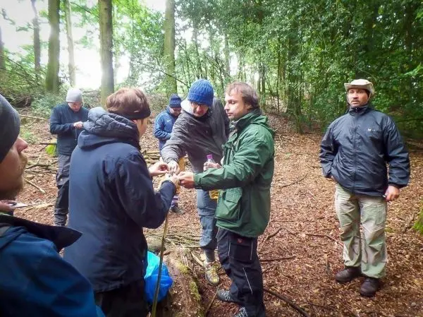 Gruppenteilnehmer tauschen Ausrüstung und Materialien im Wald