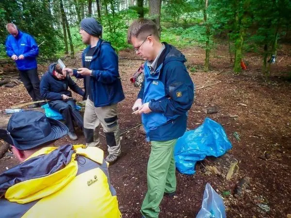 Gruppierung von Personen im Wald, einige halten Werkzeuge und Ausrüstung in den Händen